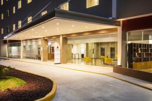 an office building with a lobby with yellow chairs at Fiesta Inn Guadalajara Periferico Poniente in Guadalajara