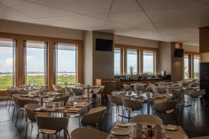 una sala da pranzo con tavoli, sedie e finestre di Fiesta Inn Cancun Las Americas a Cancún
