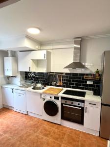 eine Küche mit weißen Schränken, einer Spüle und einem Geschirrspüler in der Unterkunft Casa Vacacional el Mirador de Picos in Serdió