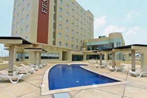 Un hotel con piscina y sillas y un edificio. en Fiesta Inn Coatzacoalcos, en Coatzacoalcos