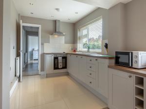 a kitchen with white cabinets and a microwave at Lamsey Cottage in Heacham