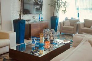 Una sala de estar con jarrones azules sobre una mesa de cristal. en Hotel Village, en Garanhuns