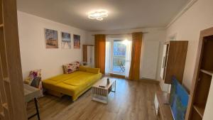 a living room with a yellow couch and a window at LCB Studio Braşov in Braşov