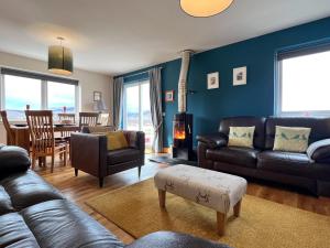 a living room with leather furniture and a dining room at Hirta Cottage in Staffin