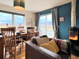 a living room with a couch and a table with a fireplace at Hirta Cottage in Staffin