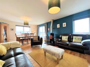a living room with black leather furniture and a dining room at Hirta Cottage in Staffin