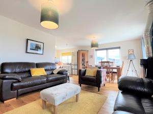 a living room with a leather couch and a table at Hirta Cottage in Staffin