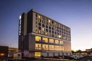 een hoog gebouw met auto's geparkeerd op een parkeerplaats bij Fiesta Inn Aguascalientes Patio in Aguascalientes