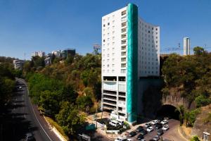 a tall white building with cars parked in a parking lot at Gamma Ciudad de Mexico Santa Fe in Mexico City