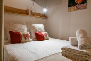 una camera da letto con un letto bianco con cuscini rossi e bianchi di Au Pied Du Château - Wifi Parking a Saint-Pierre-dʼAlbigny