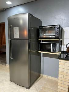 a stainless steel refrigerator next to a microwave at Studio com piscina e garagem Conforto e fácil acesso BR-101-Petfriendly, 2º andar in Joinville