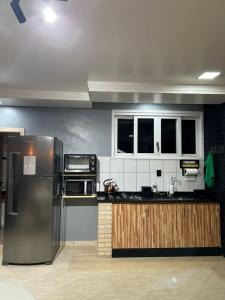 a kitchen with a stainless steel refrigerator and cabinets at Studio com piscina e garagem Conforto e fácil acesso BR-101-Petfriendly, 2º andar in Joinville