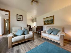 - un salon avec deux canapés blancs et un tapis bleu dans l'établissement Lag Cottage, à Dornie