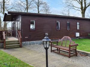 a wooden cabin with a bench and a street light at Woodpecker Lodge - Uk49149 in Little Singleton
