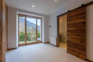 une pièce vide avec une grande porte et une fenêtre dans l'établissement Grand appartement luxueux au milieu des montagnes, à Glières-Val-de-Borne 4 autres photos