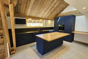 une cuisine avec des armoires bleues et un plafond en bois dans l'établissement Grand appartement luxueux au milieu des montagnes, à Glières-Val-de-Borne
