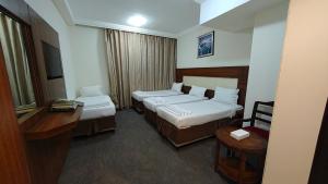 a hotel room with two beds and a desk at فندق صفوة البيت المحبس الفندقية in Al Khansāk