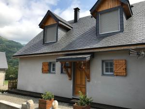 a white house with a brown door and windows at Maison "L' Ostal De Montanha" in Génos