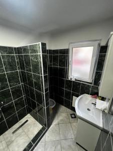 a bathroom with a black tiled shower and a sink at Sweet Home in Tuzla