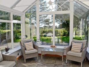 a conservatory with a table and chairs and windows at Horsepark Cottage in Girthon