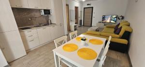 cocina y sala de estar con mesa blanca y sillas. en ApartHotel Beach & Pool Resort Alezzi langa mare, en Mamaia Nord – Năvodari