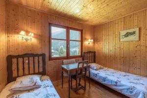 a bedroom with two beds and a table and a window at Grand Chalet au pays du Mont Blanc in Vallorcine