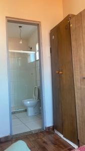 a bathroom with a toilet and a shower and a door at House in Arraial do Cabo in Arraial do Cabo
