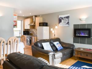 un salon avec un canapé en cuir et une cuisine dans l'établissement 15 Pebble Cottage, à Camelford