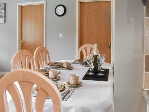 - une table avec des assiettes, des tasses et une bouteille de vin dans l'établissement 15 Pebble Cottage, à Camelford