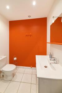 a bathroom with a toilet and an orange wall at La maison de LOUELYNE 
