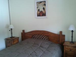 sypialnia z drewnianym łóżkiem i 2 szafkami nocnymi w obiekcie Apartamento Termas de Chillán w mieście Nevados de Chillan