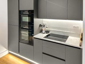 eine Küche mit weißen Schränken, einer Spüle und Geräten in der Unterkunft Ivy Cottage in Staveley