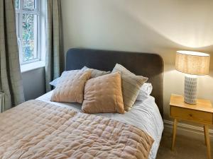 ein Schlafzimmer mit einem Bett mit Kissen und einer Lampe in der Unterkunft Ivy Cottage in Staveley