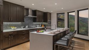 a kitchen with wooden cabinets and a large island with bar chairs at Radiance Retreat in Vail +21 photos