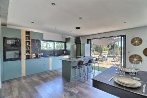 a kitchen with blue cabinets and a table with a dining room at Villa d'exception à Mauguio Piscine chauffée in Mauguio