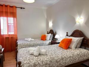 ein Schlafzimmer mit zwei Betten und orangefarbenen und weißen Kissen in der Unterkunft Dom Dinis in Trancoso