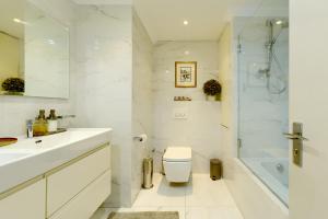 a white bathroom with a toilet and a shower at Dolphin beach Apartment -Kite beach in Cape Town +53 photos