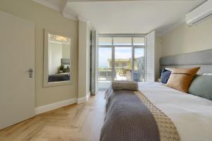 a bedroom with a large bed and a large window at Dolphin beach Apartment -Kite beach in Cape Town