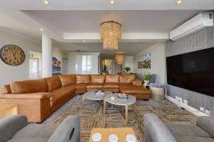a living room with a brown leather couch and a tv at Dolphin beach Apartment -Kite beach in Cape Town
