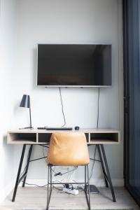 a desk with a television on a wall with a chair at VUE at 16 on Bree Apartments in Cape Town