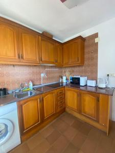 a kitchen with wooden cabinets and a sink and a dishwasher at Panorama in Calpe +22 photos