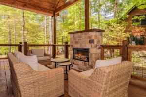 a screened porch with wicker chairs and a stone fireplace at Luxury Cabin with Hot Tub, Game Room and Movie Theater in Sevierville