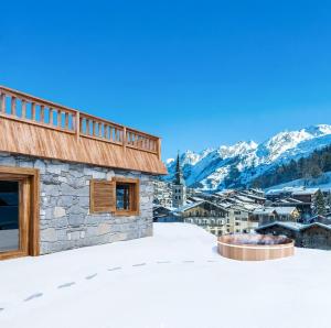 a snow covered roof of a building with mountains in the background at Chalet unique haut de gamme au centre de La Clusaz in La Clusaz +2 photos