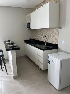 a kitchen with white cabinets and a black counter top at CF Flat 03 in Petrolina