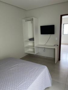 a bedroom with a bed and a flat screen tv at CF Flat 03 in Petrolina