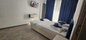 a bedroom with a bed with blue pillows and a window at Azizi Apartments Beach & Spa Resort piscina incalzita in Mamaia Nord