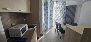 a kitchen with a microwave and a table with chairs at Azizi Apartments Beach & Spa Resort piscina incalzita in Mamaia Nord +8 photos