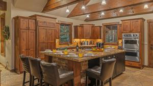 a kitchen with wooden cabinets and a large island with bar chairs at Rustic Timber Lodge in Breckenridge +16 photos