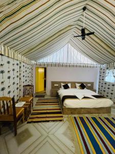 een slaapkamer met een bed en een gestreept plafond bij Osaka Desert Safari Camp in Jaisalmer