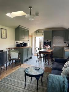 a kitchen and living room with a couch and a table at The Old Piggery - tranquil garden guest cottage in Hail Weston